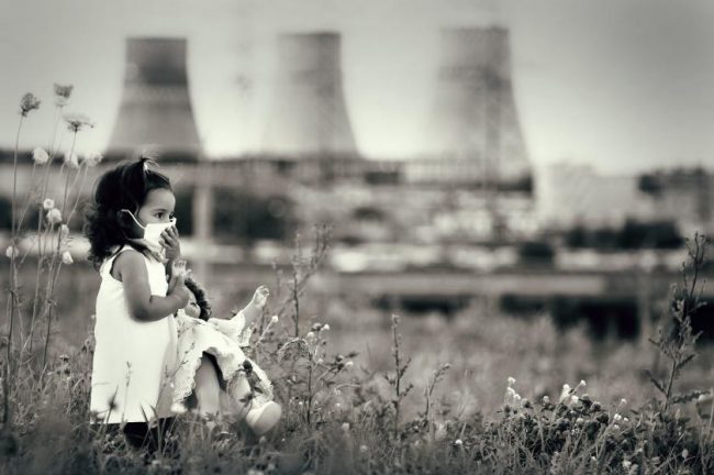Girl with Mask in Field Nuclear Cooling Towers in Background